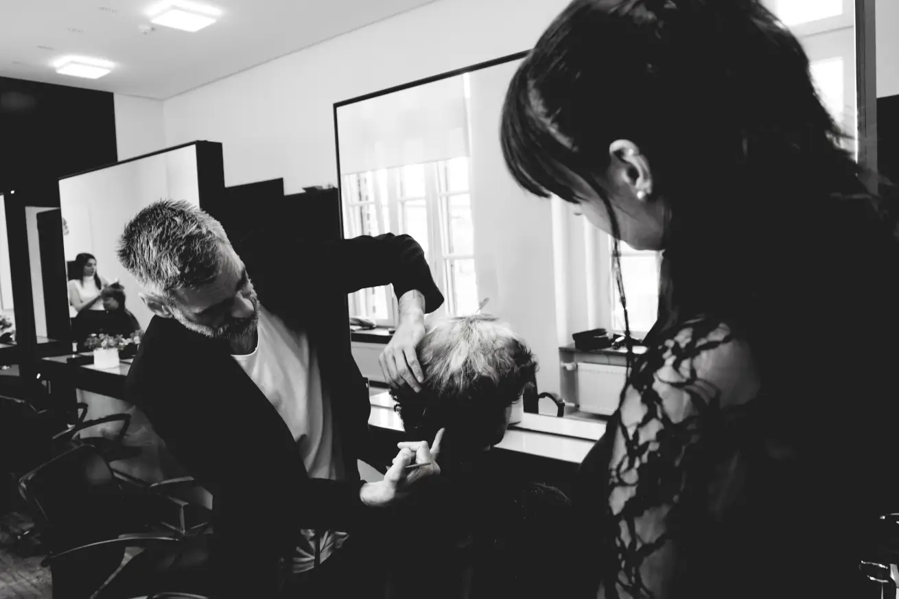 Lehrsituation mit Ausbilder, Auszubildender und Model im Hair-Salon.